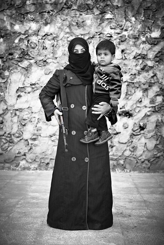 صورة العام : منقبة سورية تحمل ابنها وسلاحها صورة رقم 1