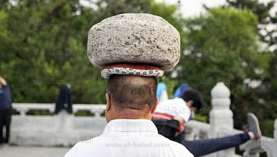  صور رجل صيني يتجول بصخرة على راسه لكي يخسر وزنه صورة رقم 2