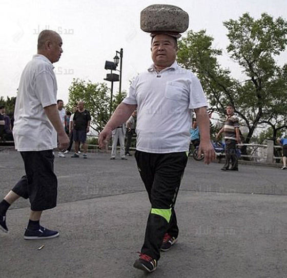  صور رجل صيني يتجول بصخرة على راسه لكي يخسر وزنه صورة رقم 3