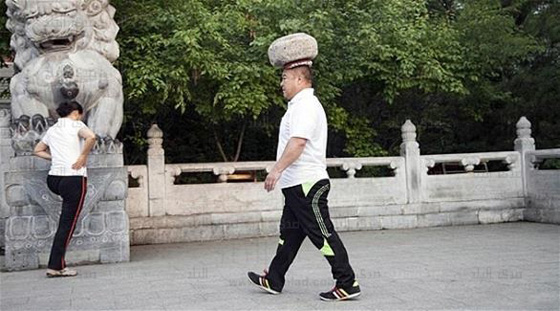  صور رجل صيني يتجول بصخرة على راسه لكي يخسر وزنه صورة رقم 4