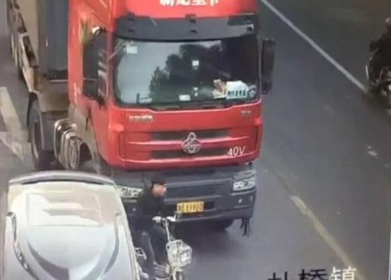 فيديو وصور: سائق دراجة نارية متهور ينجو من الموت سحقا بعجلات شاحنة صورة رقم 1